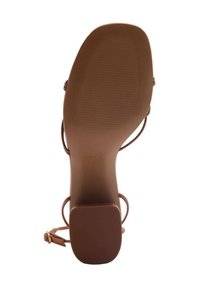 Brown heeled sandal with a smooth, matte sole. Features thin straps and a square heel, with a textured bottom for grip.
