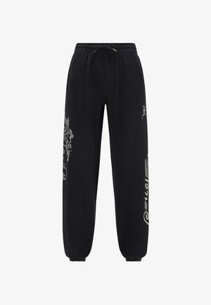 Pantalones de chándal negros con cintura ajustable, puños estrechos y diseños gráficos de colores claros en la pierna izquierda y el costado. Textura suave.
