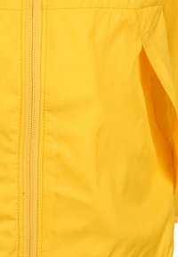 Giacca leggera gialla con una texture liscia, dotata di una zip centrale e tasche laterali. Il design è semplice, senza motivi visibili.