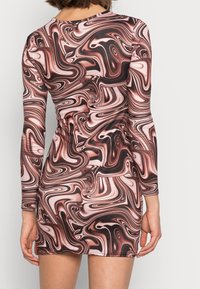 Pitkähihainen, vartalonmyötäinen minimekko, joka on valmistettu sileästä kankaasta ja jossa on pyörteilevä kuvio ruskean, mustan ja posliinin sävyissä.