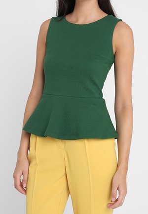 Top peplum verde con tessuto testurizzato, scollatura rotonda e design senza maniche, abbinato a pantaloni gialli su misura.