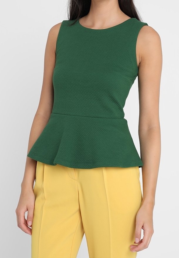 Zelený peplum top s texturovanou tkaninou, kulatým výstřihem a bezrukávovým provedením, doplněný žlutými šitými kalhotami.