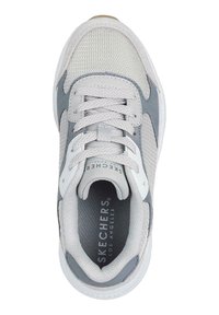 Zapatilla Skechers con parte superior de malla gris claro y detalles en gris oscuro, punta redonda y suela texturizada. Los cordones están bien ajustados.