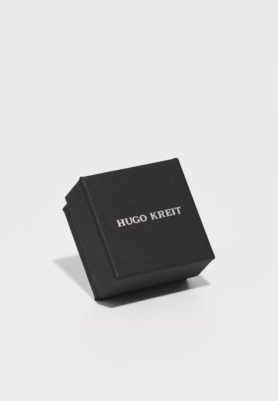 Black square gift box with a matte finish, featuring silver text that reads "HUGO KREIT" on the front. Box has sharp edges and a compact design.
