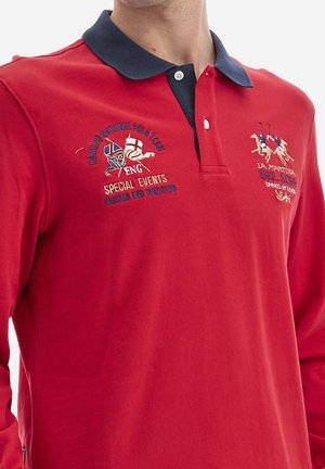 Camisa polo de manga larga roja con cuello azul marino, que presenta diseños bordados: logotipos del Equipo Nacional de Polo de Inglaterra y de La Martina. Material de algodón.