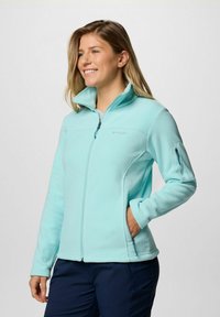 Giacca in pile azzurro chiaro con colletto alto, chiusura frontale con zip e tasche laterali. Presenta una piccola tasca con zip sul maniche sinistro.