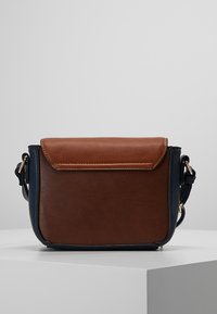 Brązowa i granatowa torebka noszona na crossbody, wykonana z imitacji skóry, charakteryzująca się usztywnionym kształtem, zapięciem na klapkę oraz elementami wykończenia w złotym kolorze.