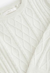 Bílý svetr s pleteným vzorem ve tvaru diamantu, s pružným výstřihem a manžetami s jemným povrchem. Štítek viditelný na límci.