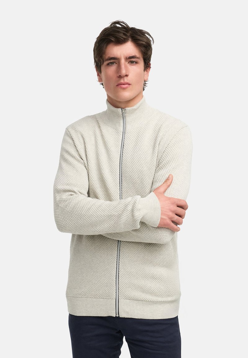 Lichtbeige zip-up trui met een gestructureerd patroon, hoge kraag en geribde manchetten. Kenmerkt zich door een centrale rits met contrasterende donkere afwerking.
