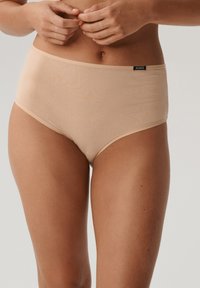 Nude wysokie figi wykonane z gładkiego materiału z miękkim wykończeniem; posiadają elastyczny pas i minimalistyczne logo z przodu.