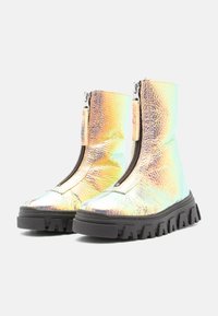 Bottines iridescentes avec une finition métallique texturée, dotées d'une fermeture éclair à l'avant et de semelles en caoutchouc noir épaisses avec un profil dentelé.