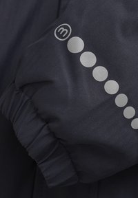 Ärmeln einer navyblauen Steppjacke mit Fischgrätmuster, ausgestattet mit einem silbernen Logo und kreisförmigem Muster entlang des Arms. Elastischer Bund.