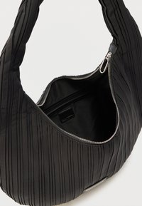 Czarna plisowana torebka na ramię z szerokim paskiem i otwartym srebrnym suwakiem, odsłaniającym czarne wnętrze z małą kieszonką zapinaną na zamek.