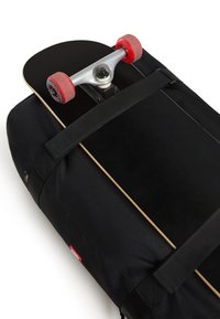 Zwarte duffeltas met bovenop een skateboard bevestigd, voorzien van rode wielen, zilverkleurige beslagdelen en een volledig zwarte grip tape oppervlak.