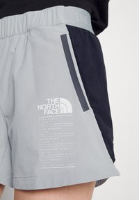 Ljusgrå och marinblå atletiska shorts med andningsbart mesh-sidopanel, elastisk midja och tryckta klättringsdetaljer.