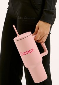 Conteneur à boisson rose avec une poignée, une paille et un couvercle noir contrasté. Présente le texte en gras "Couture" en rose. Fini lisse et mat.