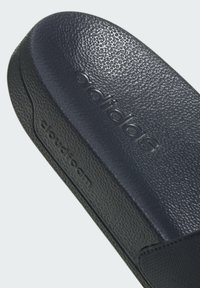 Semelle intérieure Cloudfoam noire d'Adidas avec une surface texturée et un logo en relief. Le matériau semble synthétique et durable.