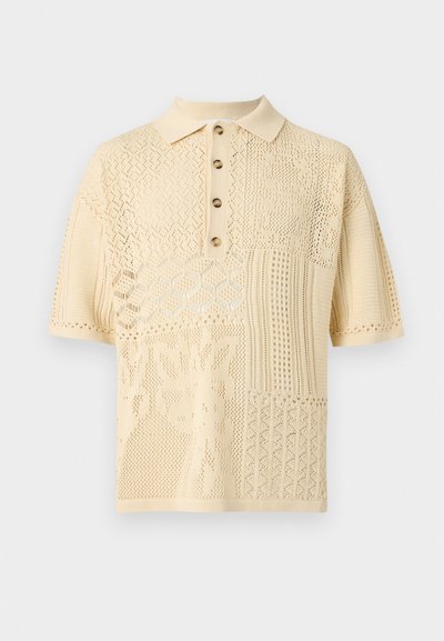 Πουκάμισο πόλο πλεκτό με κοντά μανίκια σε κρεμ απόχρωση, με διακοσμητικό σχέδιο ανοιχτής πλέξης και τέσσερα καφέ κουμπιά στο πατιλέτα.