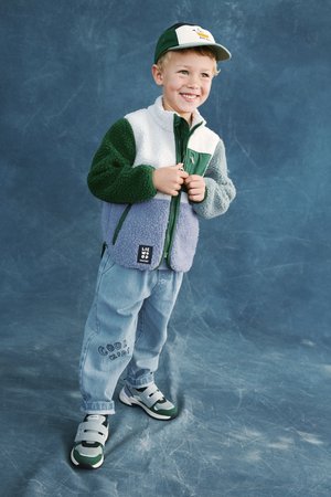 Fliisist jakk roheliste, valgete ja lavendlivärviliste paneelidega. Hele sinised teksapüksid mustriga "Cool Kids". Hallid ja rohelised tossud.