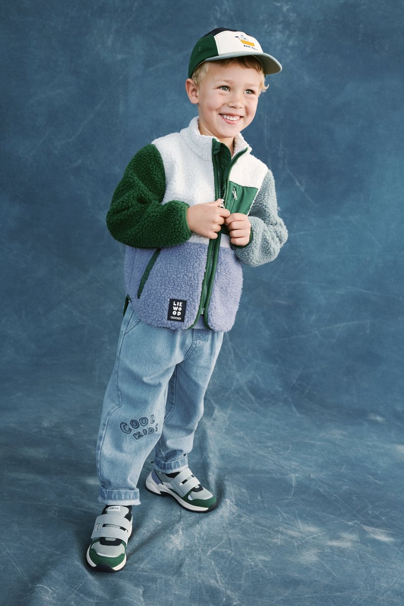 Ζακέτα fleece με πράσινα, λευκά και λεβαντίνια πάνελ. Ανοιχτό μπλε τζιν παντελόνια με κέντημα «Cool Kids». Γκρι και πράσινα αθλητικά παπούτσια.