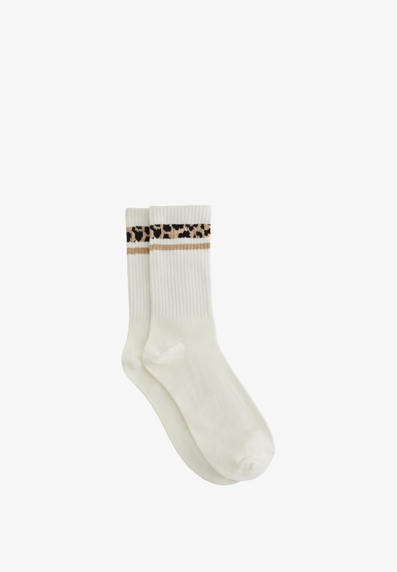Paire de chaussettes blanches montantes avec des bords côtelés et une bande imprimé léopard marron et noir près du haut.