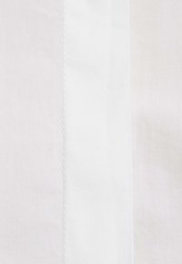 Gros plan sur un tissu en coton blanc avec une couture verticale centrée.