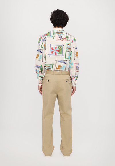 Long-sleeve shirt with colorful beach-themed prints, cotton fabric. Paired with beige, loose-fit trousers featuring back pockets.