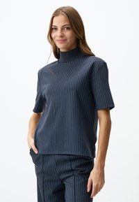 Granatowa bluzka z krótkim rękawem w paski z wysokim kołnierzem, wykonana z gładkiego materiału, z cienkimi kontrastowymi pionowymi paskami.