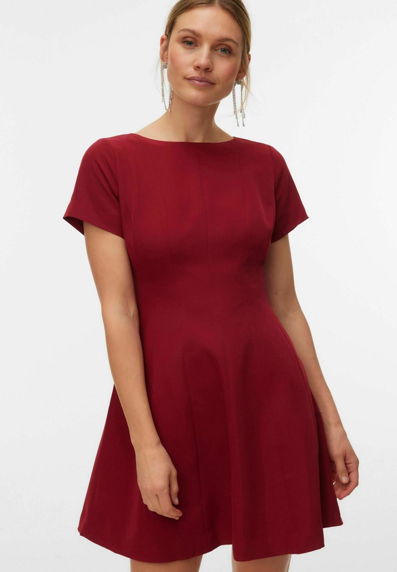 Bordo haljina kratkih rukava s pripijenim korzetom i širokom suknjom. Glatki materijal i suptilni detalji šavova sprijeda. Duljina ruba iznad koljena.