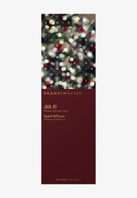 Emballage du diffuseur de parfum Skandinavisk Jul en rouge profond avec du texte doré, sommet à motifs avec des lumières festives floues et des symboles.