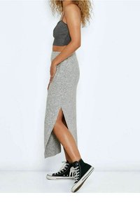 Jupe maxi en tricot gris avec une fente haute, associée à des baskets montantes en toile noires. Portée avec un crop top noir.