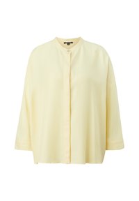 Blouse jaune clair à manches longues avec col rond et patte de boutons cachée, présentée sur fond blanc uni.