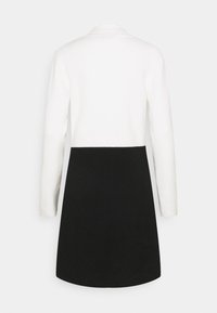 Long-sleeved dress featuring a white top and a black skirt. Made of soft fabric with a smooth texture and a rounded neckline.