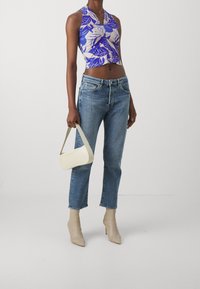 Korta ärmlös topp med blå och beige bladmönster, bleka blå raka jeans, krämfärgad handväska och hudfärgade spetiga ankelstövlar.