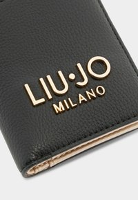 Portafoglio in pelle nera testurizzata con lettering dorato "LIU•JO MILANO" sul fronte, caratterizzato da un design semplice ed elegante e da cuciture a contrasto.