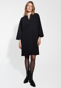 Zwarte wollen blend jurk met een V-hals, verlaagde schouders en driekwart mouwen, met een rechte pasvorm die boven de knie valt.