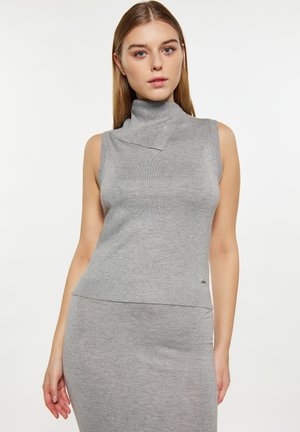 Top grigio senza maniche con collo alto in maglia testurizzata, caratterizzato da un collo asimmetrico unico e un orlo a costine. Tessuto morbido e elastico.