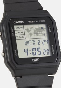 Montre numérique Casio avec un bracelet en plastique noir, un cadran rectangulaire, un rétroéclairage LED et un affichage avec une carte du monde. Affiche l'heure et la date.