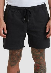 Pantaloni corti neri in cotone con vita elastica e cordino. Presentano un design semplice e pulito e arrivano sopra il ginocchio.