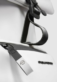 Witte rugzak met grijze accenten, voorzien van een voorrits en zwarte bandjes. Opvallend logodetail aan de rits-trekker en zijkant van de rugzak.