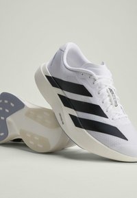 Paar weiße Laufschuhe mit schwarzen Streifen, dicken gepolsterten Sohlen und "ADIZERO" Branding auf der Zunge und Seite.