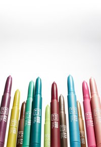 Colorful ZMINA brand eye sticks arranged upright in a row, featuring shades of purple, yellow, green, blue, brown, red, pink, and peach.