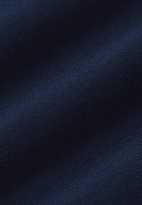 Ciemnoniebieska tkanina o prążkowanej teksturze, z równomiernie rozmieszczonymi wypukłościami. Materiał wydaje się miękki i elastyczny, układając się w gładkie krzywizny.