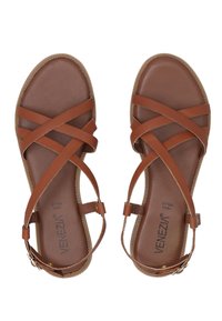 Bruine leren sandalen met kruislings straps, een platte zool en een enkelgesp. Glad oppervlak met een gevlochten randafwerking.