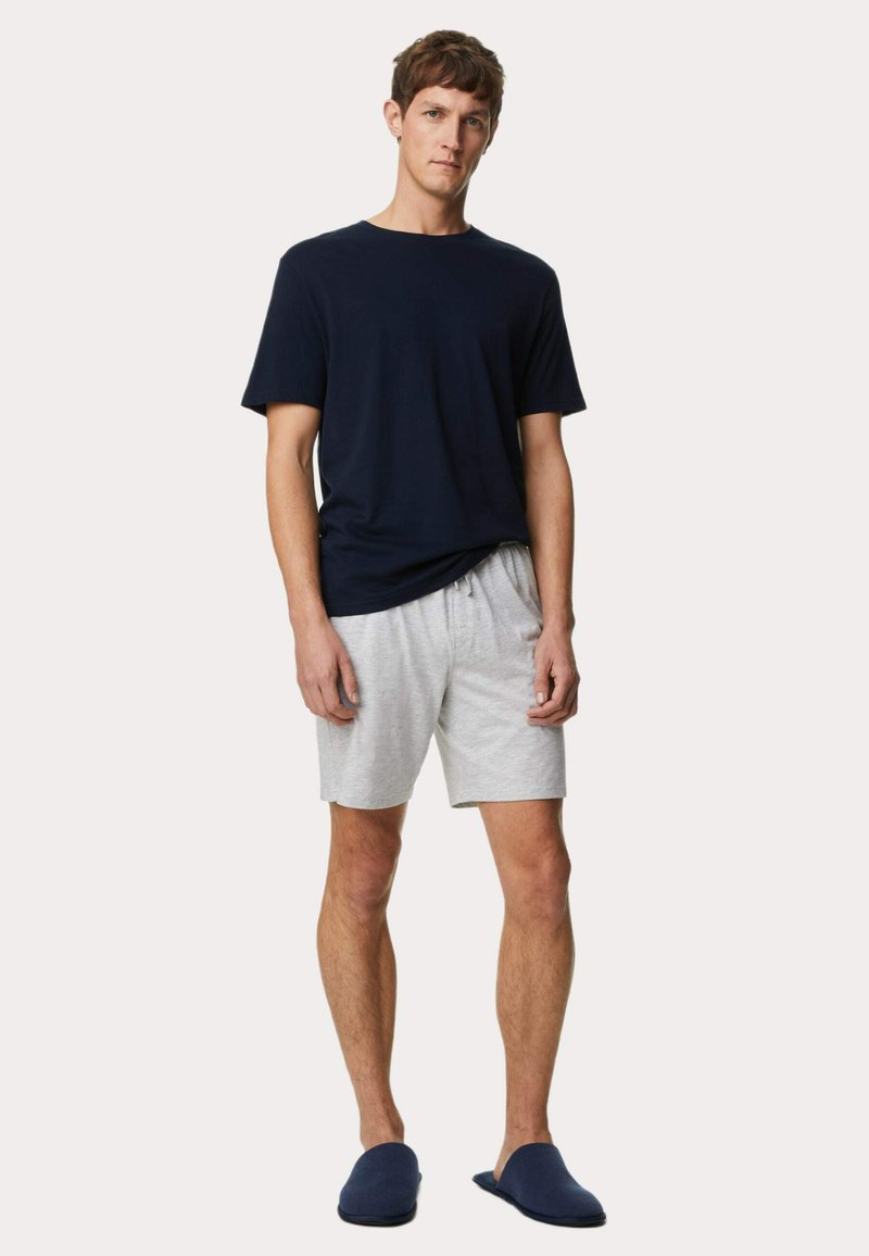 Camiseta de manga corta azul marino, pantalones cortos grises con cordón, y zapatillas azules; tejido de algodón, corte relajado, ropa de casa informal adecuada para el hogar.
