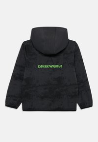 Veste à capuche noire avec un motif texturé, dotée d'un grand logo vert "Emporio Armani" au dos. Tissu doux avec des poignets côtelés.