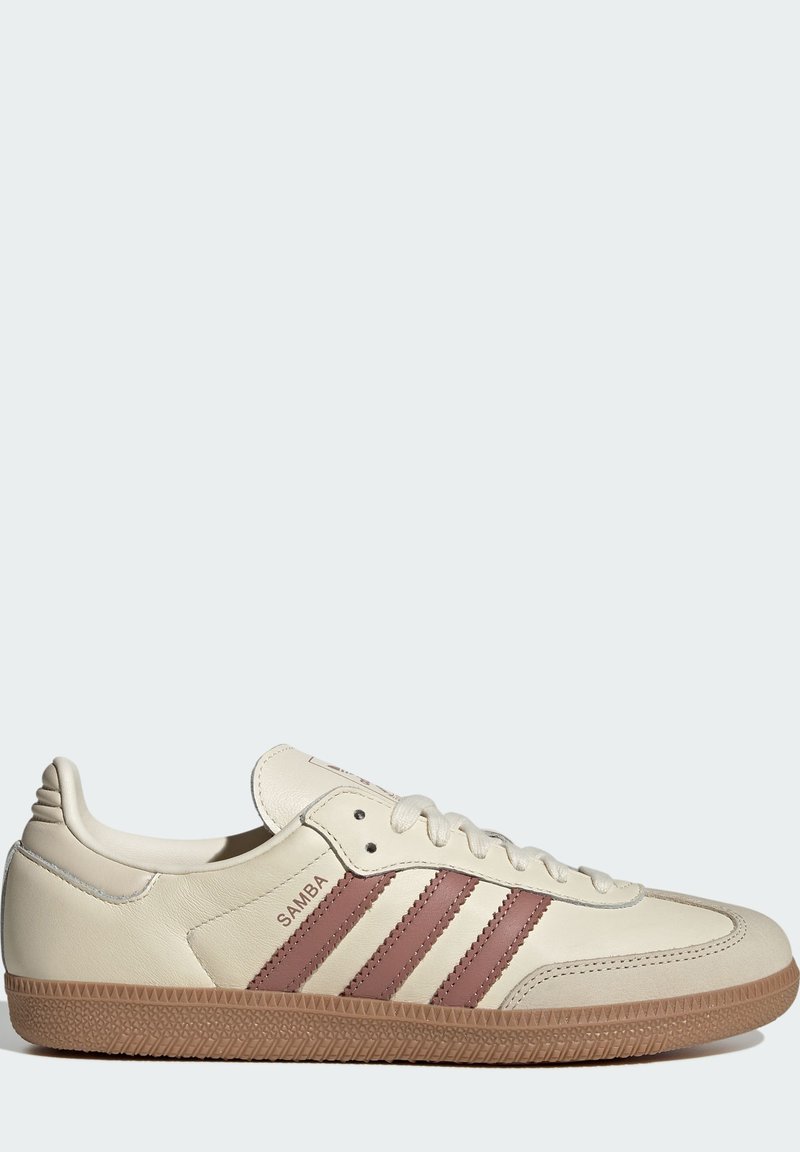 Krämfärgade lädersneakers med tre mörkröda ränder, platta snören och strukturerad gummisula. Har märket "SAMBA" på sidan.