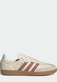 Beige skinnsko med tre burgunder striper, rund tå og strukturert gummisåle. Har snøring og preget merkenavn "SAMBA."