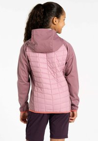 Rosa gesteppte Jacke mit Kapuze, verfügt über eine glatte Vorderseite, gerippte Bündchen und kontrastierende korallenfarbene Akzente am Saum. Getragen mit dunklen Shorts.