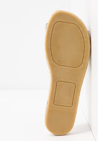 Semelle d'une chaussure taille 37 avec semelle en caoutchouc marron texturée, marquée "Made in Spain", posée contre une surface blanche.